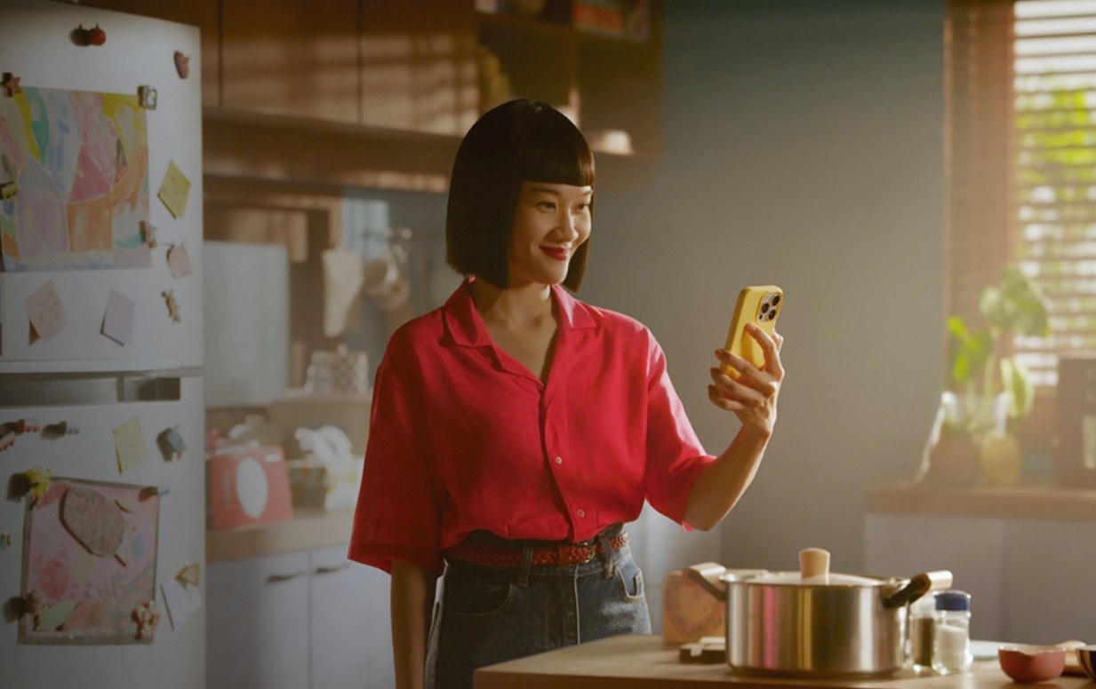 Mujer sonriendo mientras mira su celular en una cocina